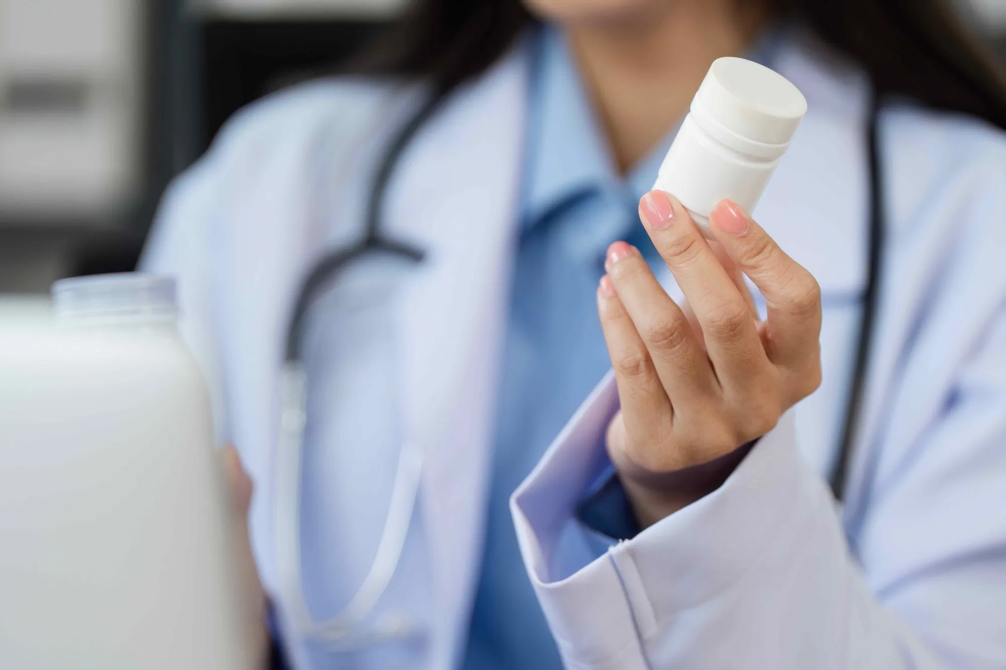 A pharmacist in a white coat holding a bottle of medicine